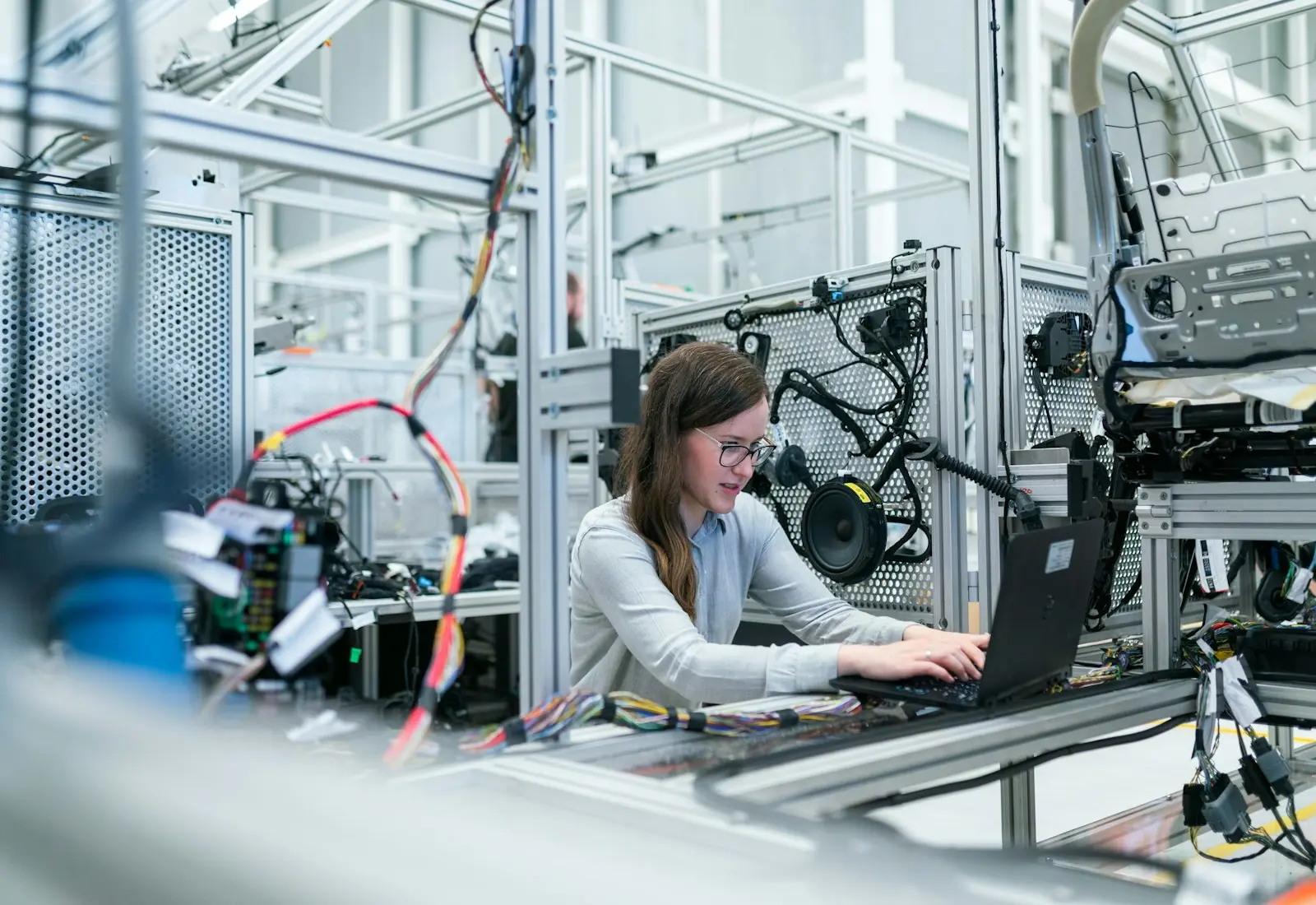 An engineer using a laptop beside equipment on a factory floor