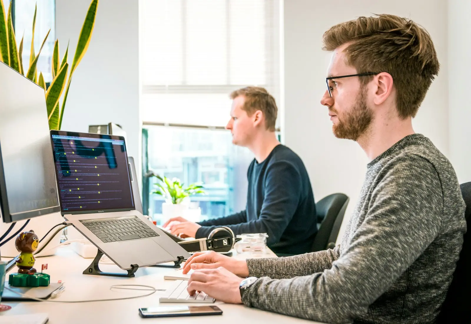 Two colleagues working at computers in a bright office