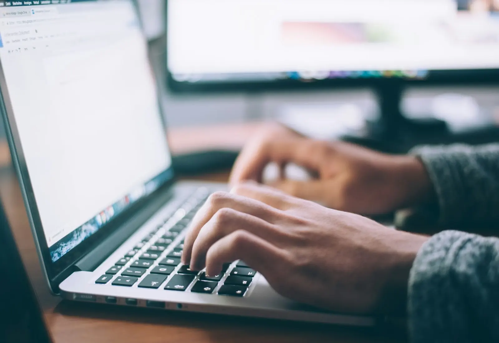 Hands typing on a laptop in an office