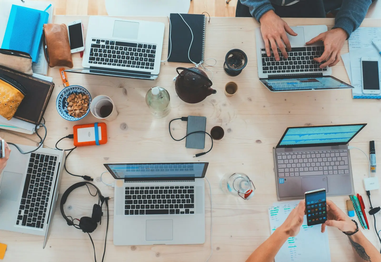 Laptops and notebooks spread across a team work table